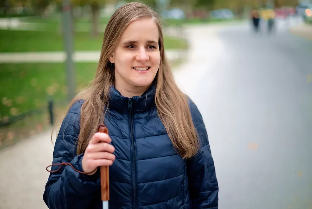 A blind disabled woman is smiling while outdoors at a park